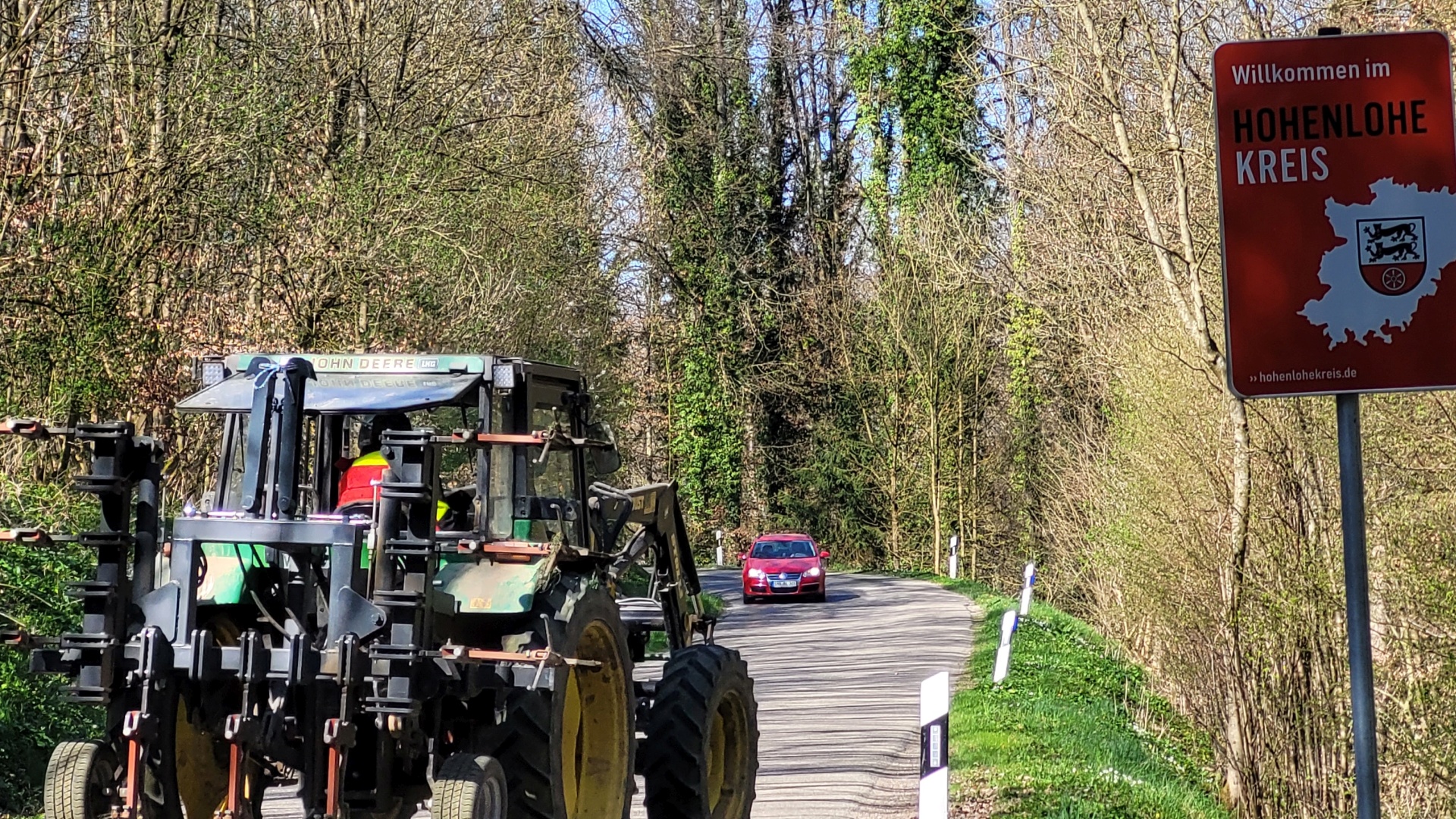 Traktor auf Landstraße fährt am Willkommensschild des Hohenlohekreises vorbei.