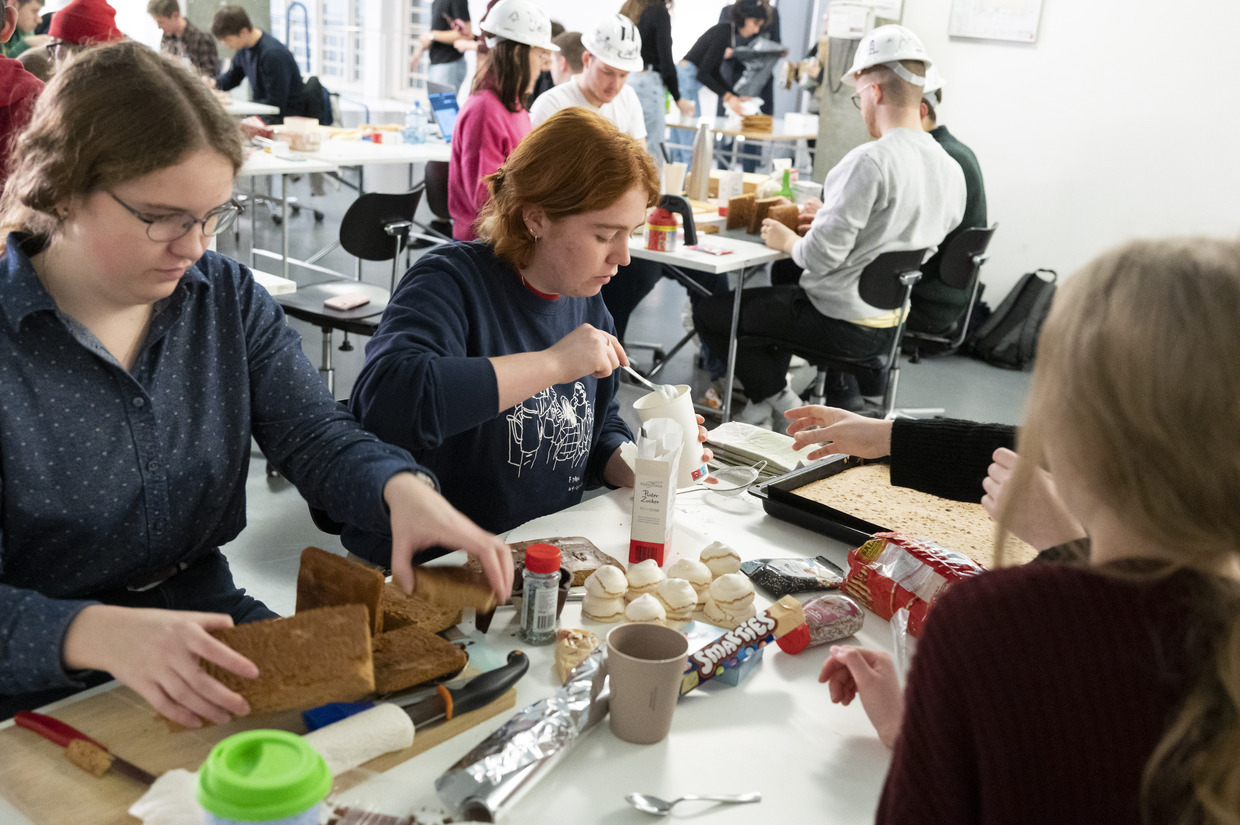 Drei Frauen sitzen an einem Tisch und arbeiten an Lebkuchen. 