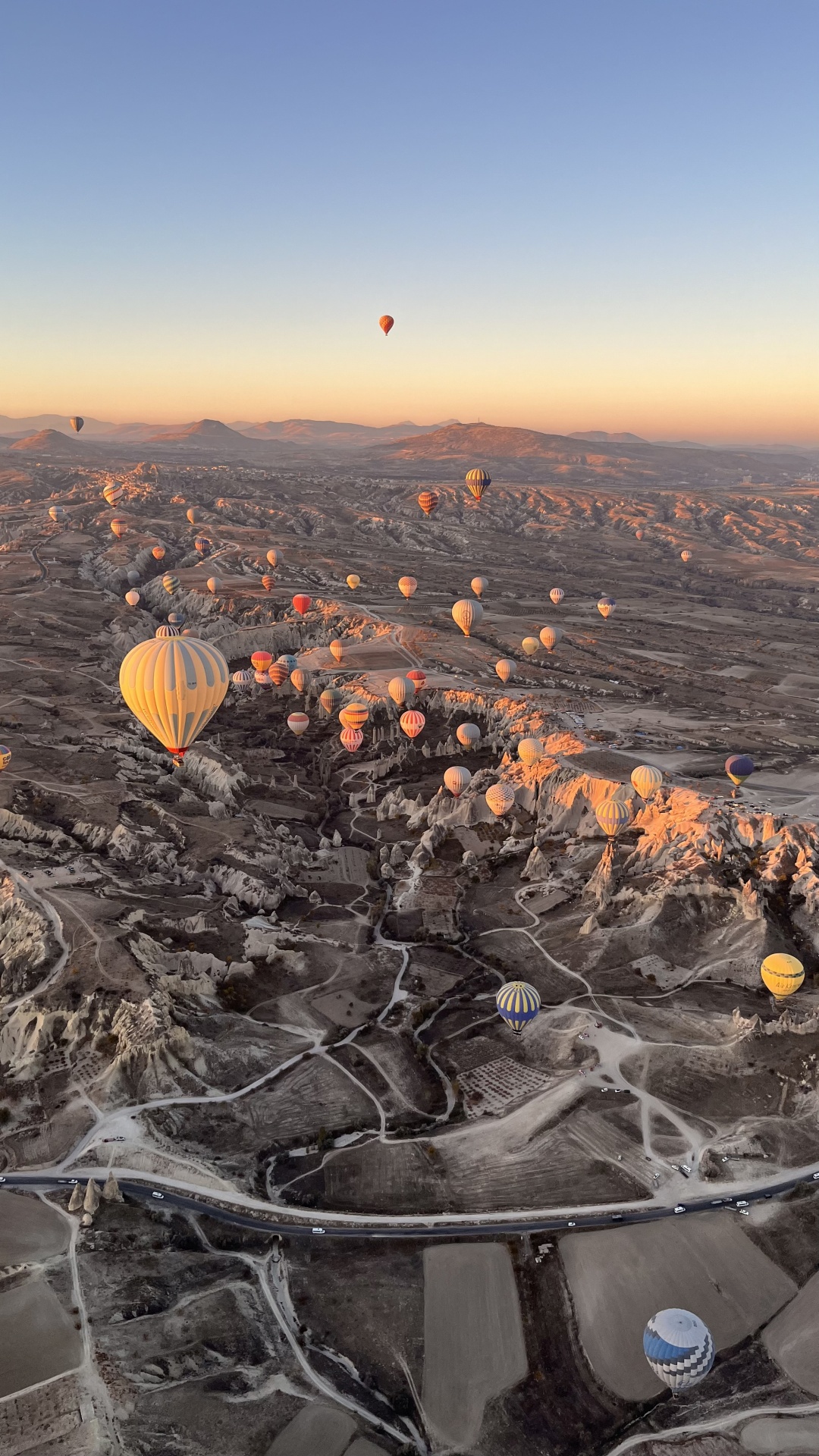 Heißluftballons über einer Landschaft bei Sonnenaufgang.