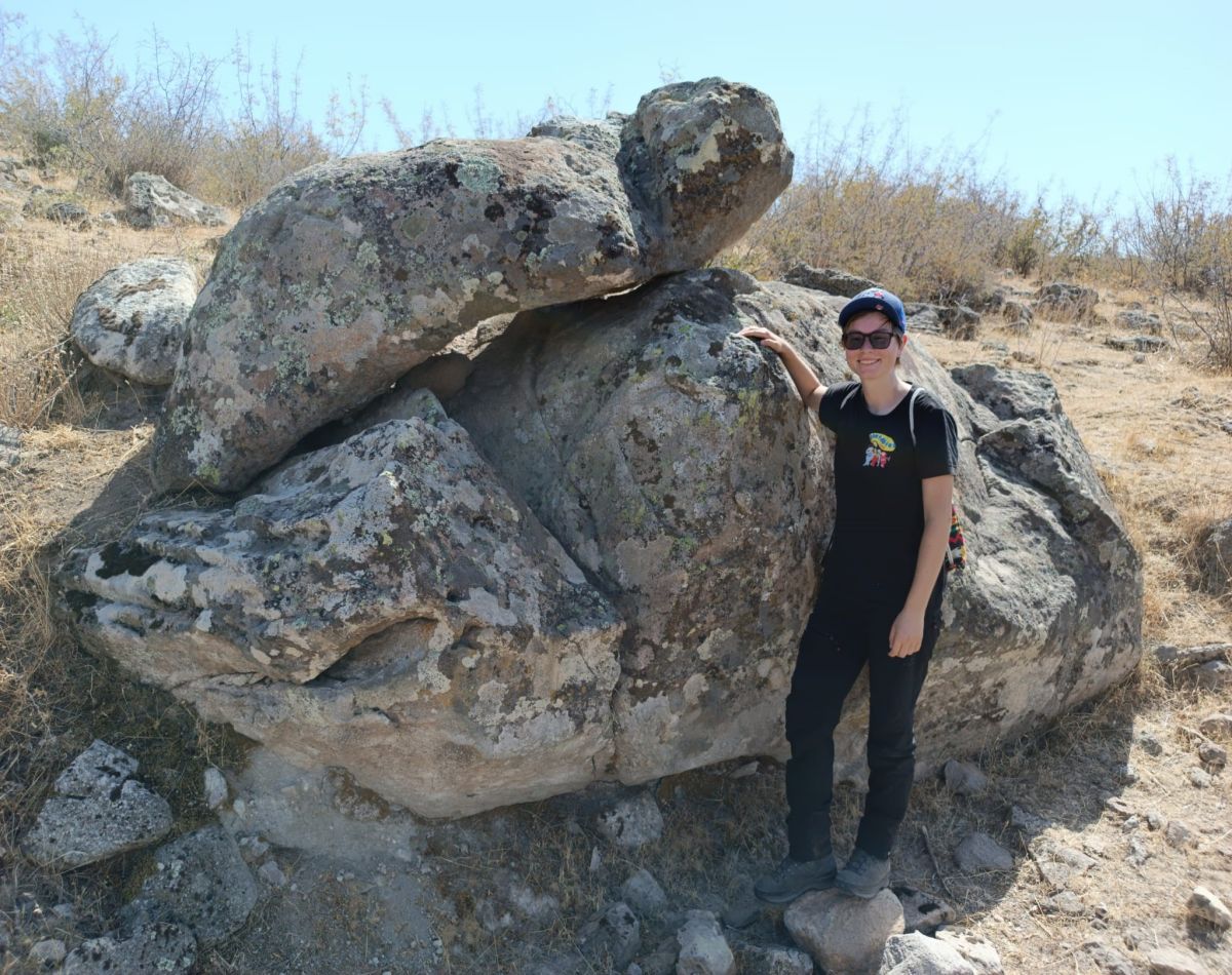 Elisabeth Kral posiert vor einem großen Stein. 