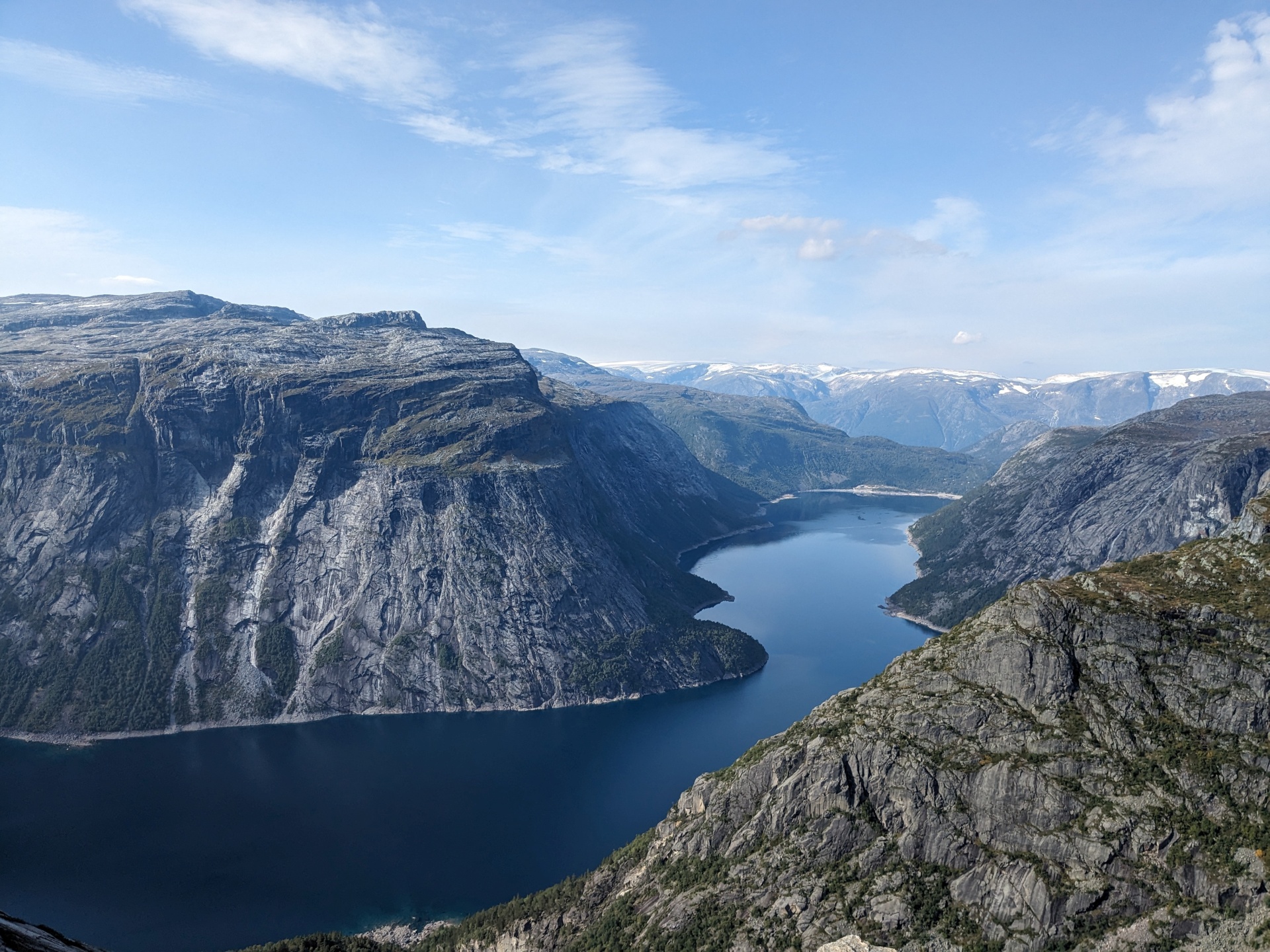 Atemberaubender Blick auf einen Fjord, umgeben von hohen, felsigen Bergen unter klarem Himmel.