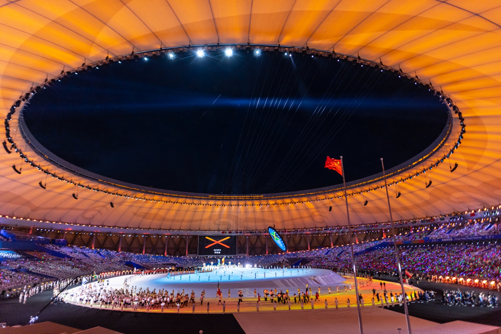 Bild der Eröffnungsfeier, die in einem großen, offenen Stadion stattfindet. 