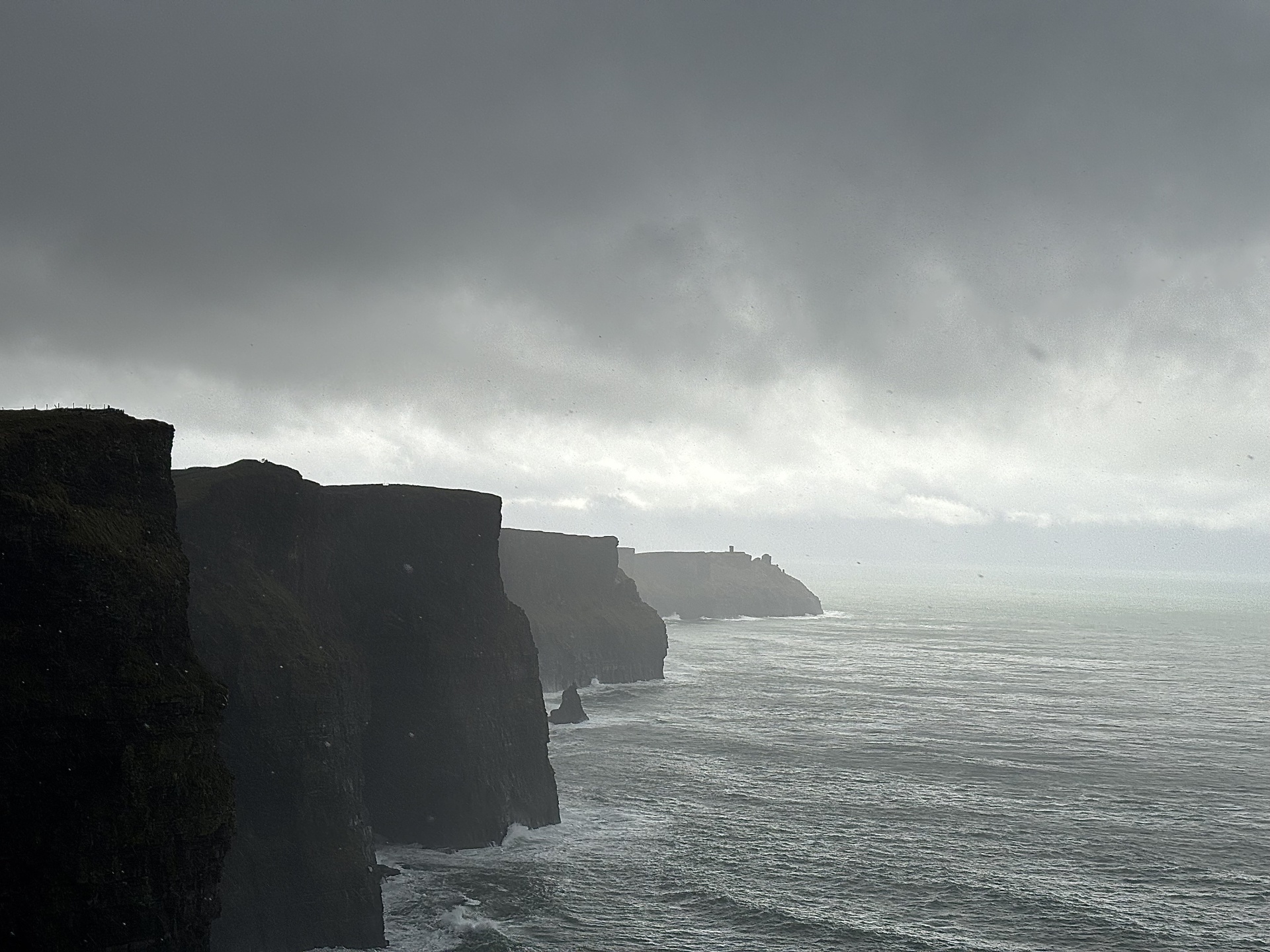 Dramatische Klippen am Meer unter wolkenverhangenem Himmel.