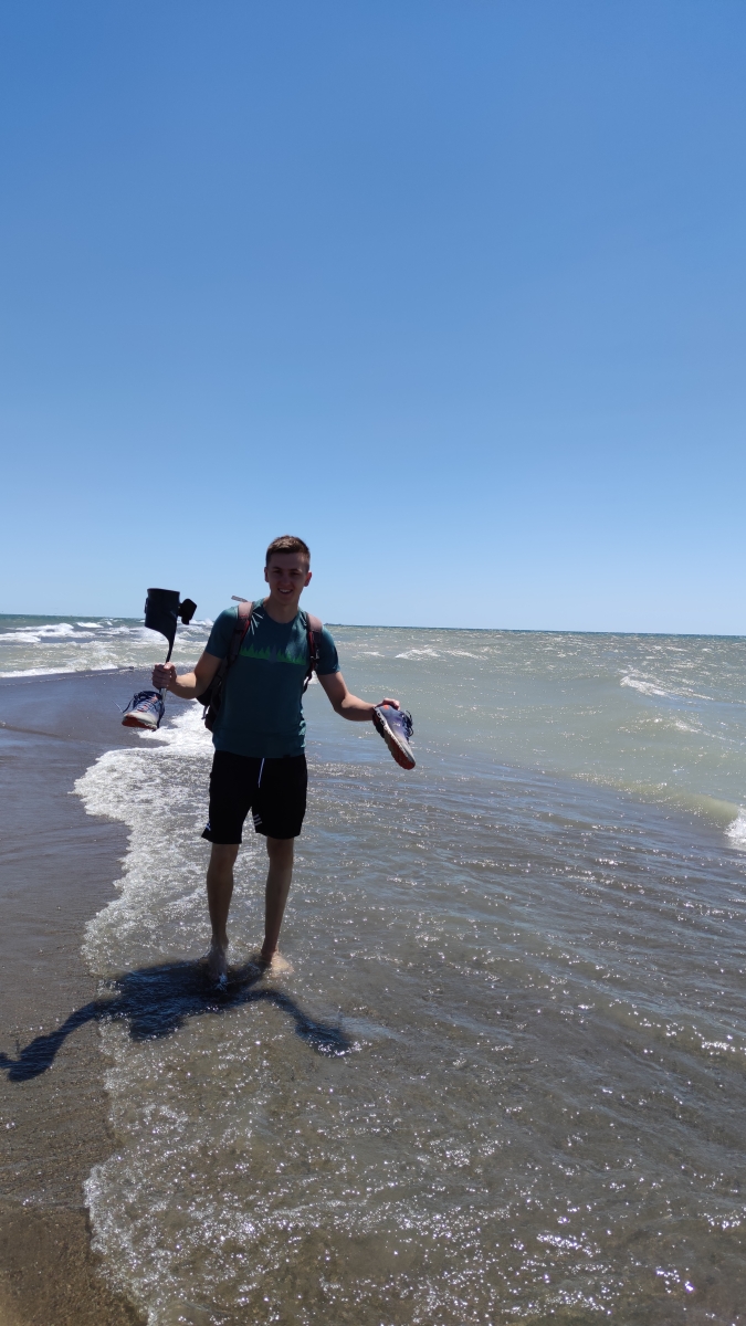 Kristof läuft am kanadischen Strand mit seinen Schuhen in der Hand. 