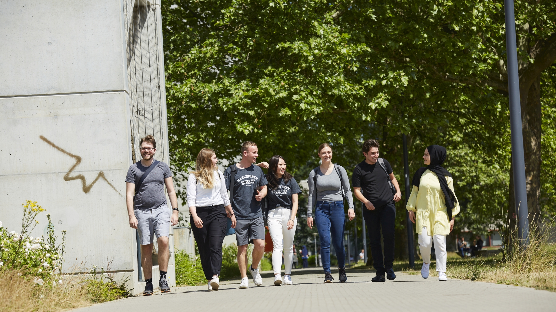 Mehrere Studierende laufen im Sommer über den Campus. 