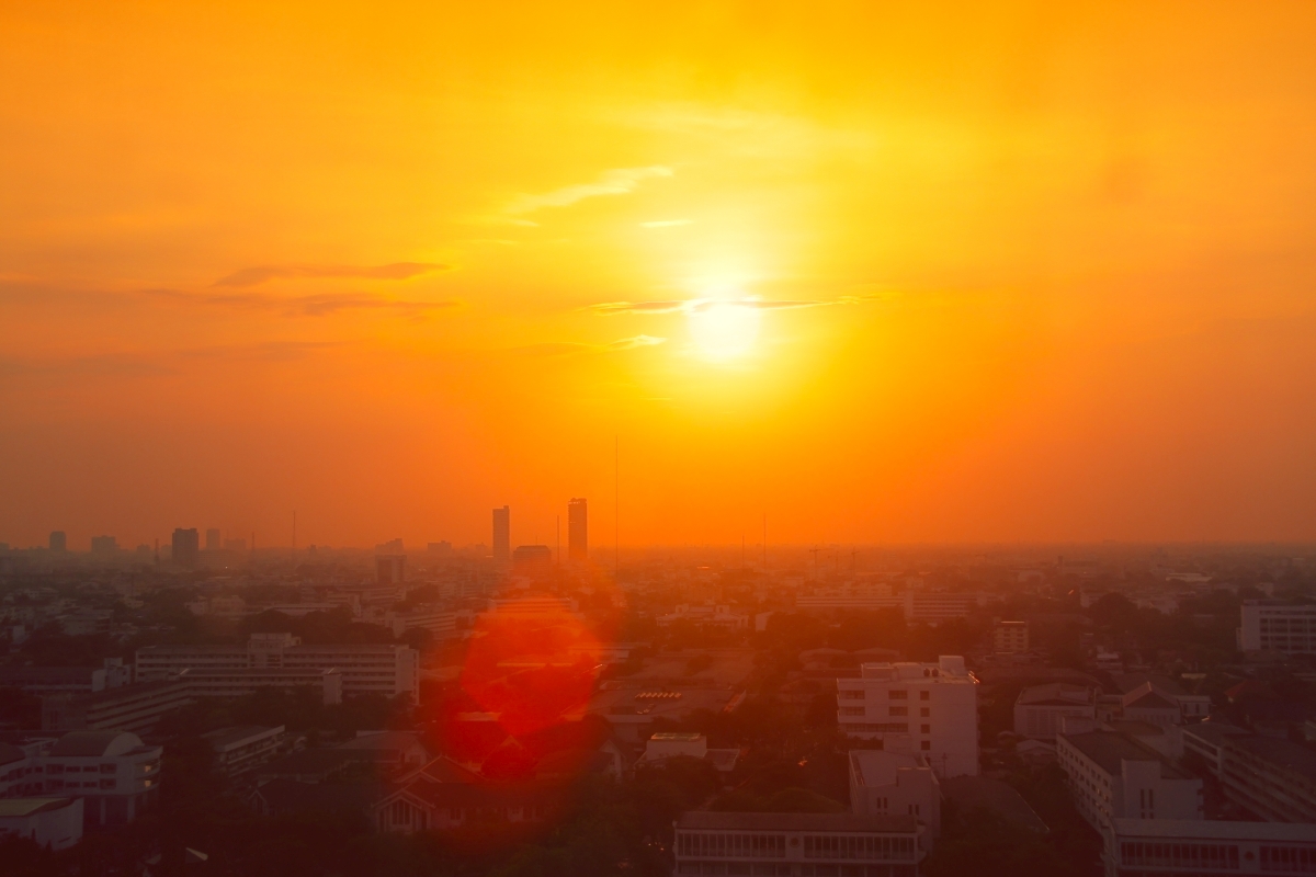 Foto einer Stadt bei Sonnenuntergang. Sie ist in ein dunkles rot-orange getaucht. 