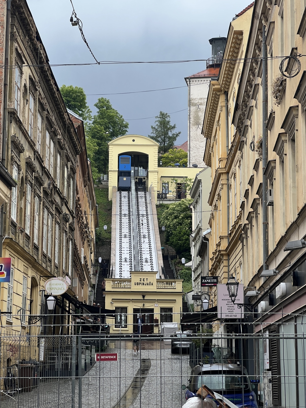 Standseilbahn in einer engen europ&auml;ischen Altstadtstra&szlig;e mit historischen Geb&auml;uden.