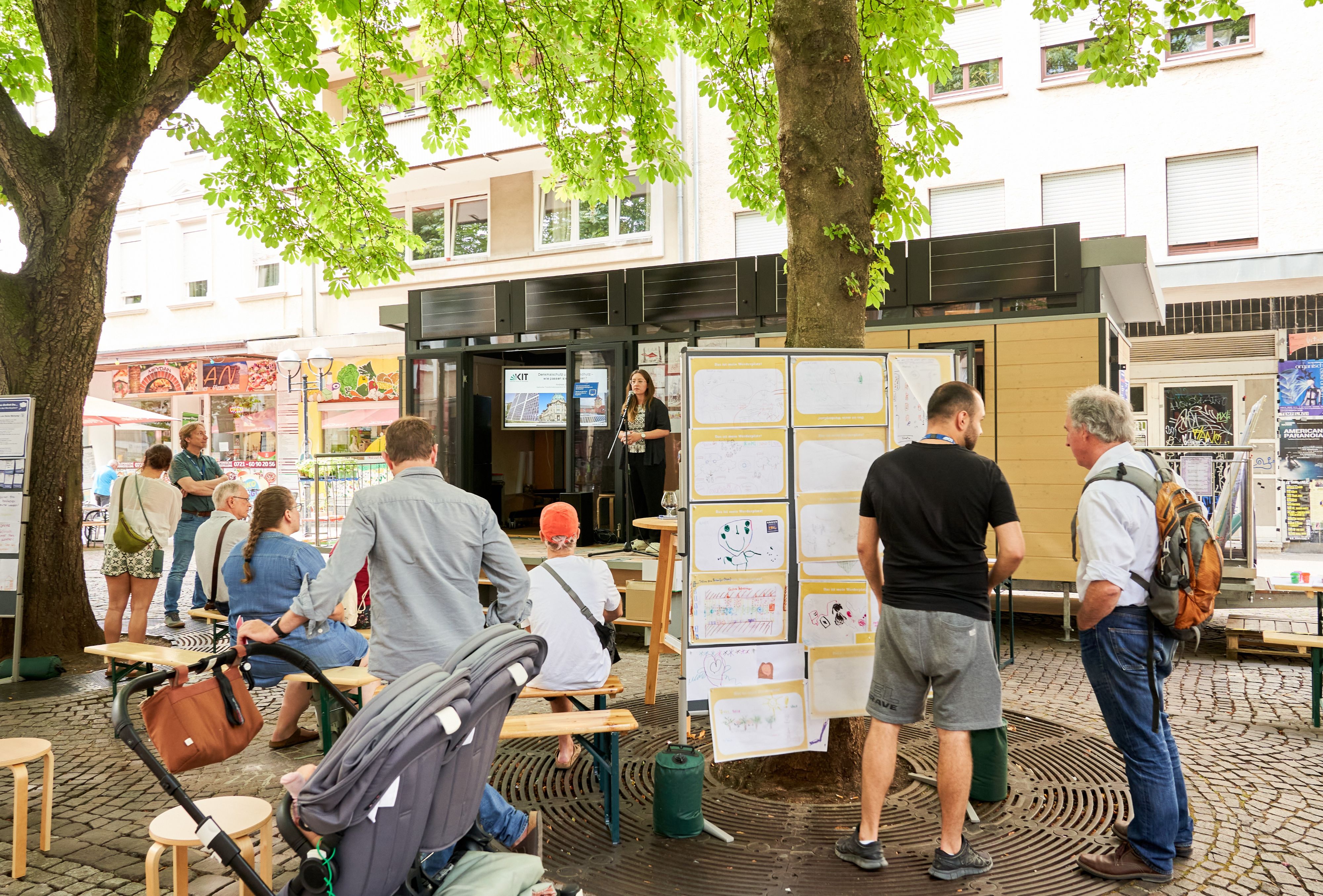 Einige Menschen stehen vor dem MobiLab. Dort spricht eine Frau in ein Mikrofon.