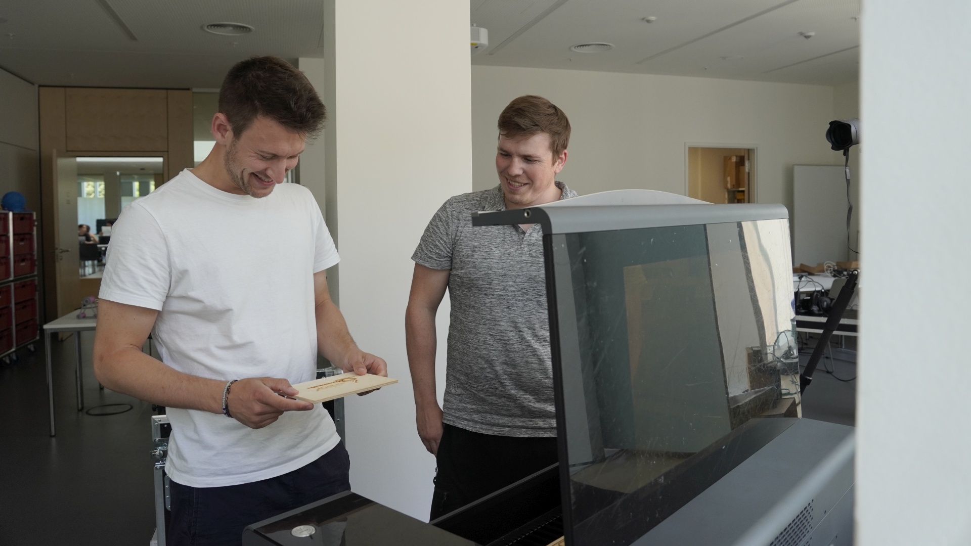 Niklas Treml steht mit einem Kollegen vor einem Lasercutter.