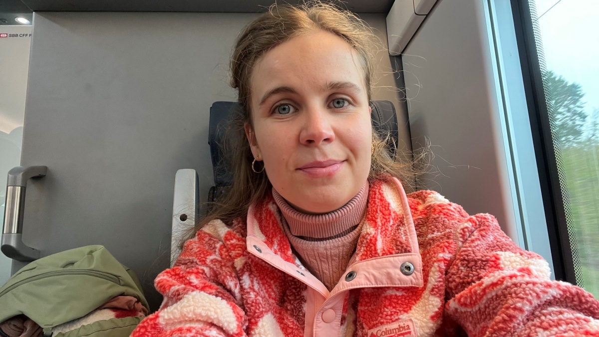 Felicitas sitzt im Zug und lächelt in die Kamera.