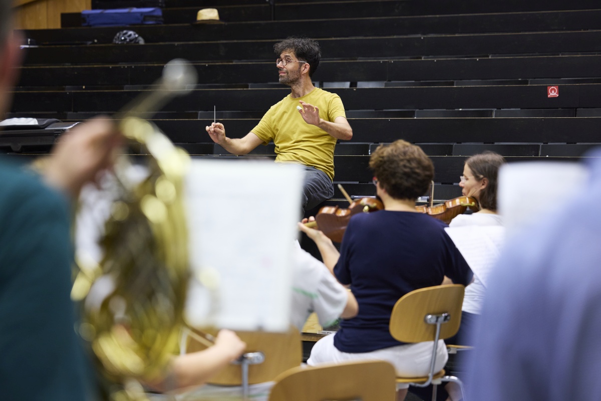 Fran&ccedil;ois Salignat steht vor dem Orchester und dirigiert es.
