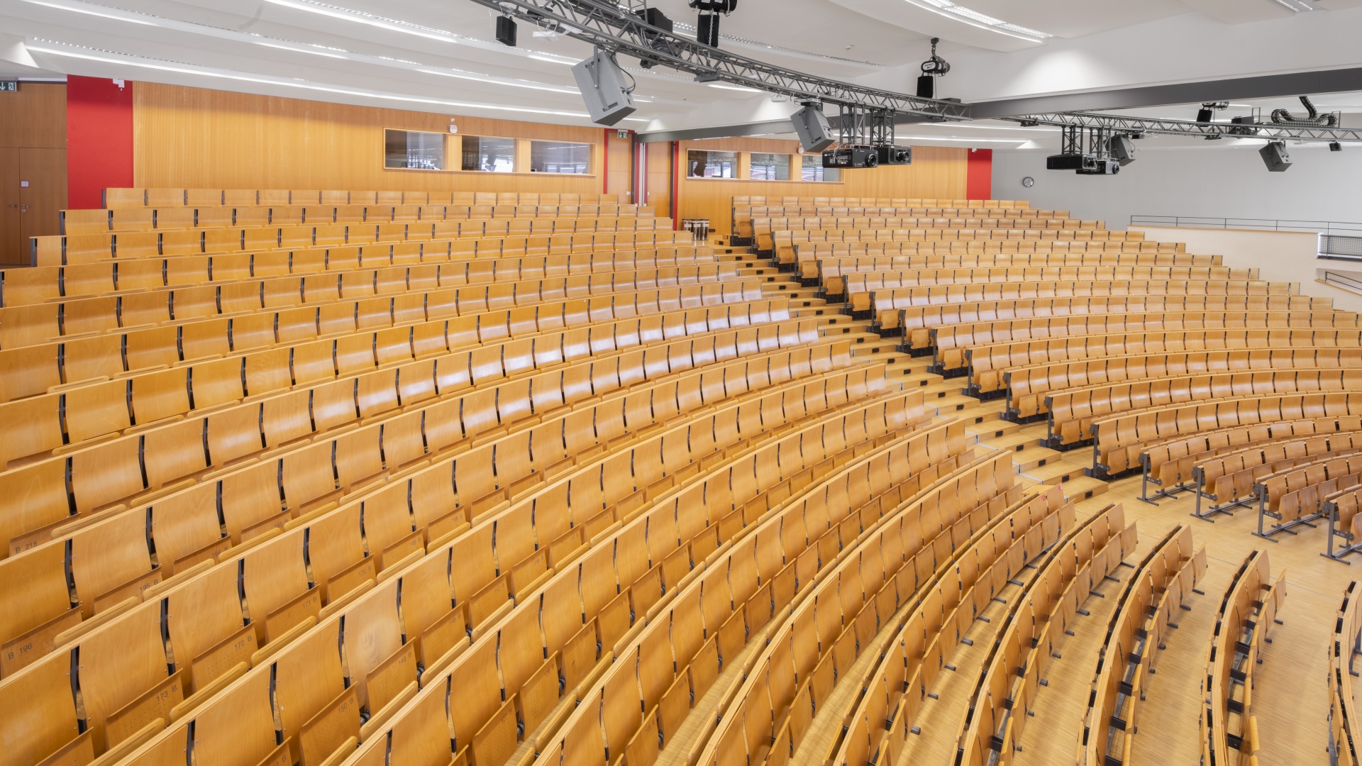 Leerer Hörsaal mit hölzernen Sitzreihen in einem Universitätsgebäude.