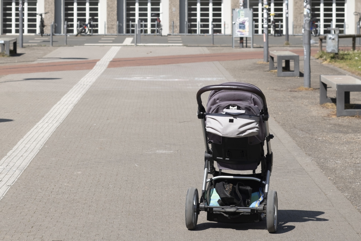 Ein Kinderwagen steht allein auf einem Fußweg. 