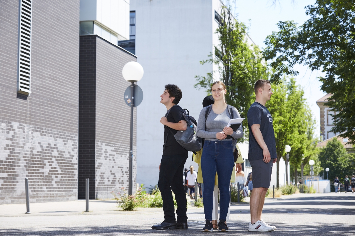 Vier Studierende stehen Rücken an Rücken zueinander und schauen in unterschiedliche Richtungen.