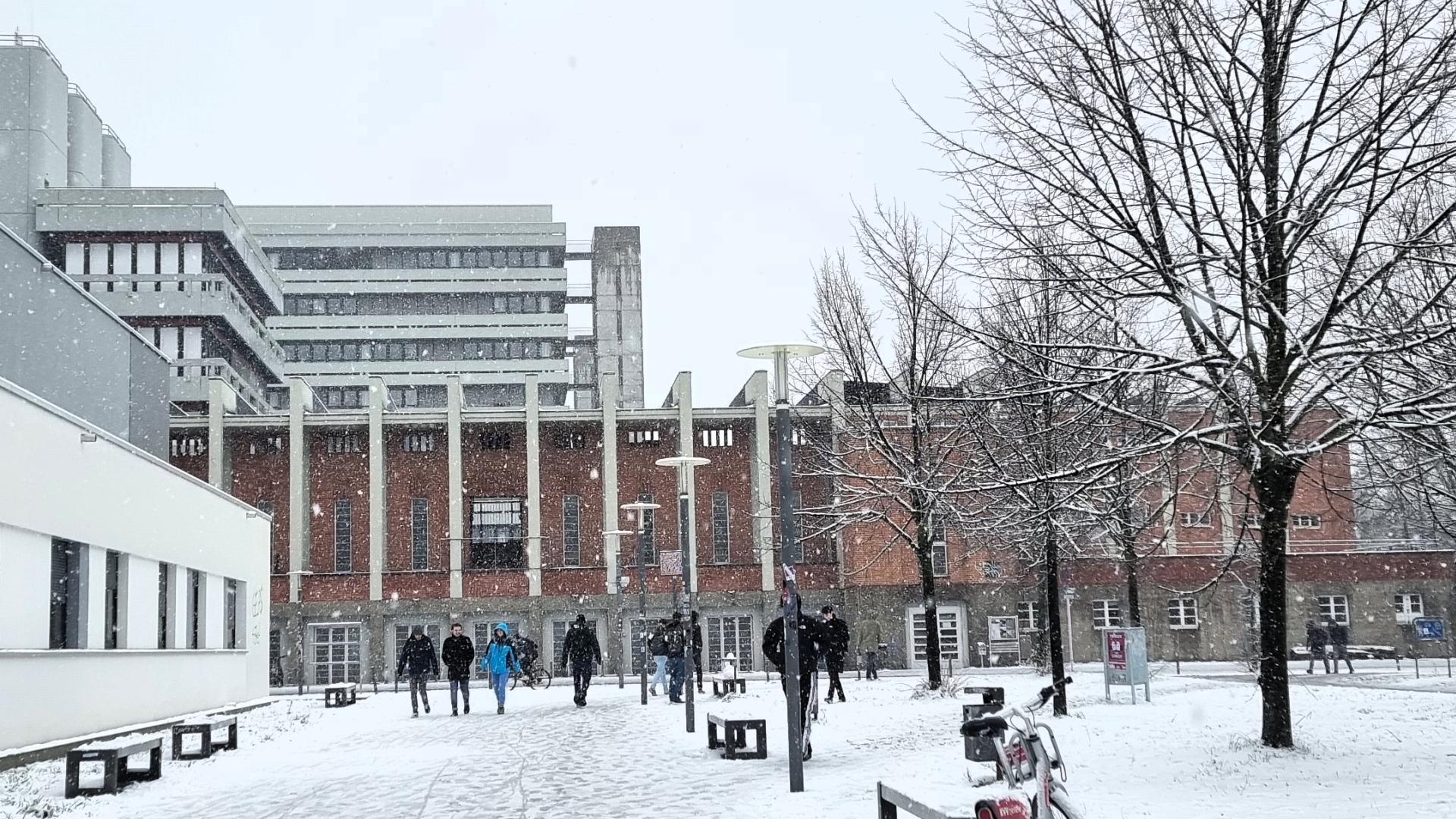 Studierende laufen über den schneebedeckten Campus. 