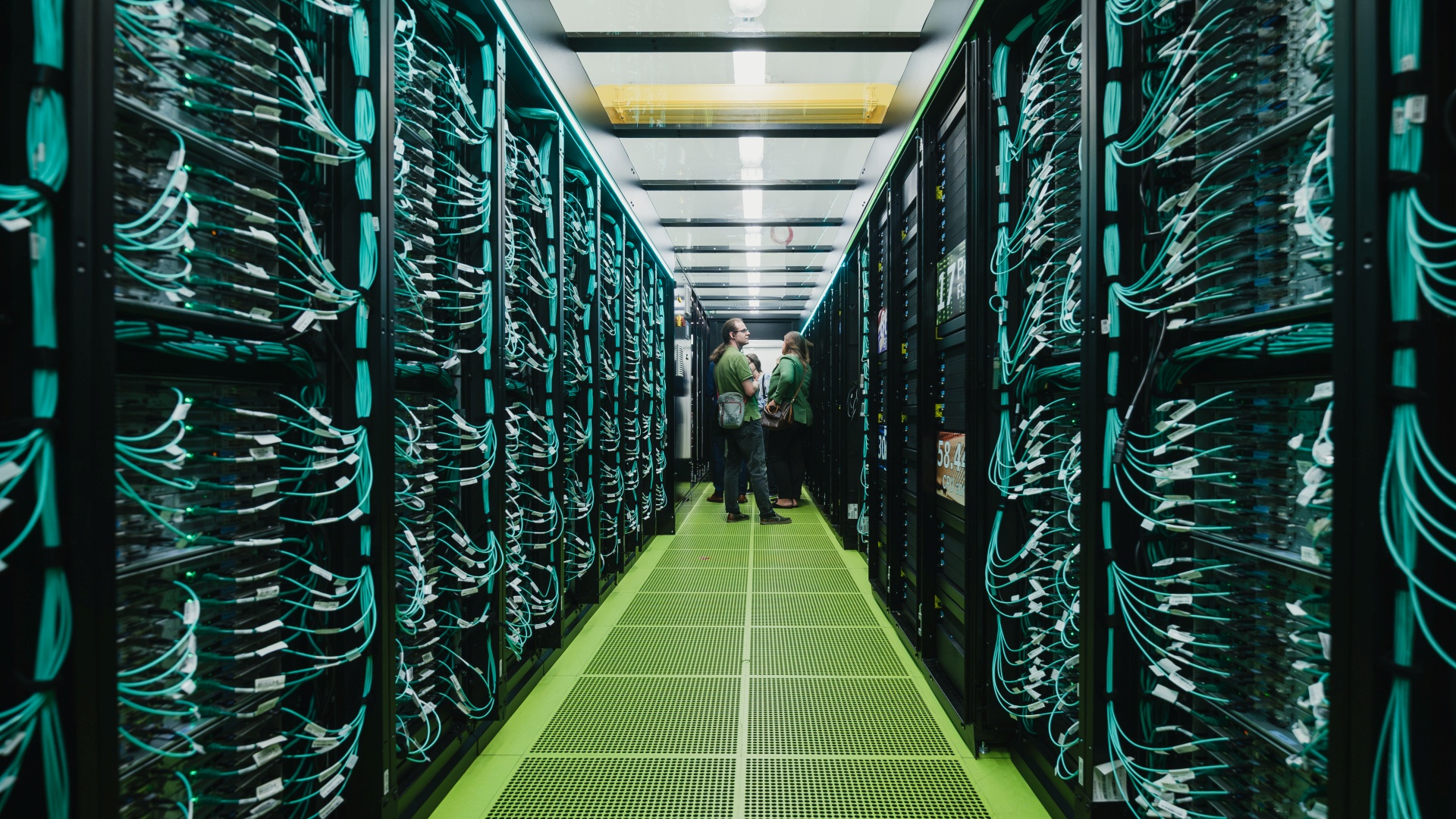 Foto eines Ganges der Supercomputer-Lauwerke. Im Hintergrund stehen Menschen.