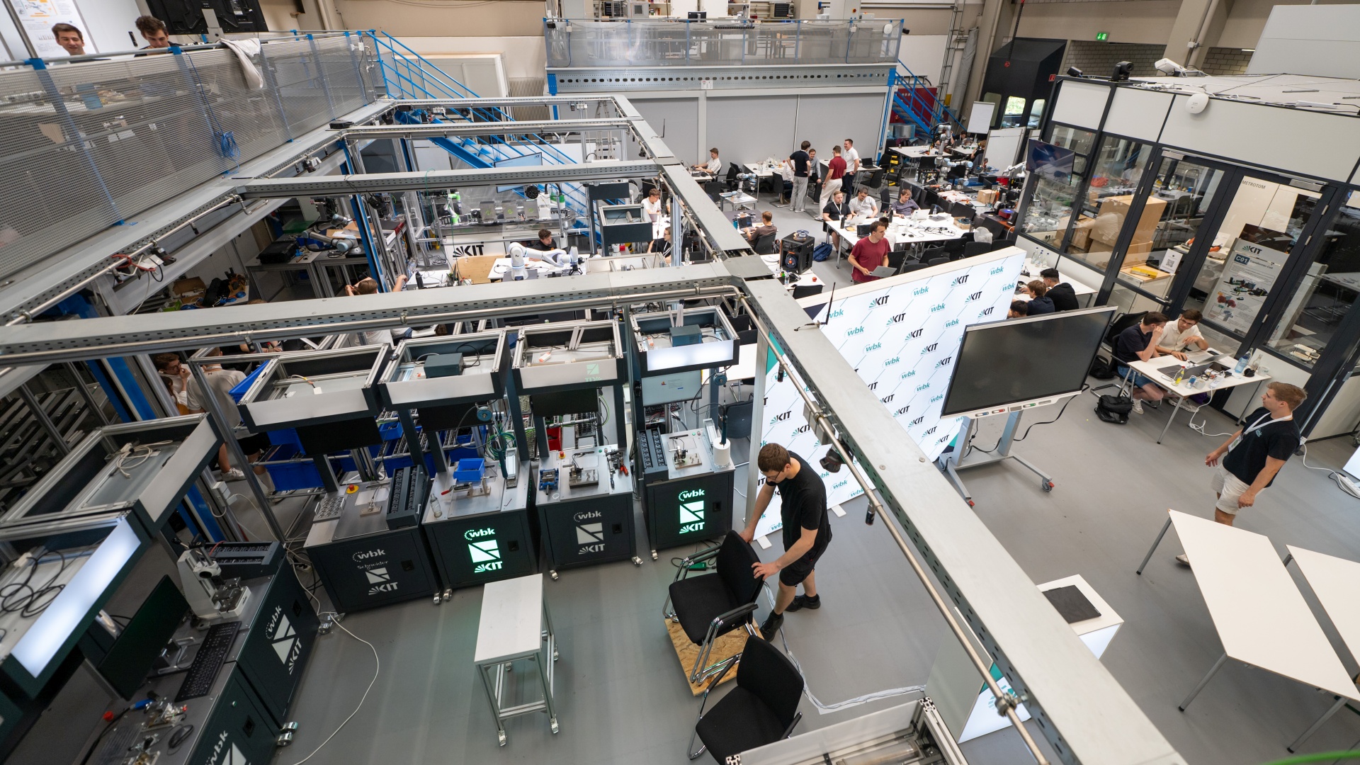 Moderner Technik-Laborraum mit Studierenden an Forschungsstationen und Messgeräten.